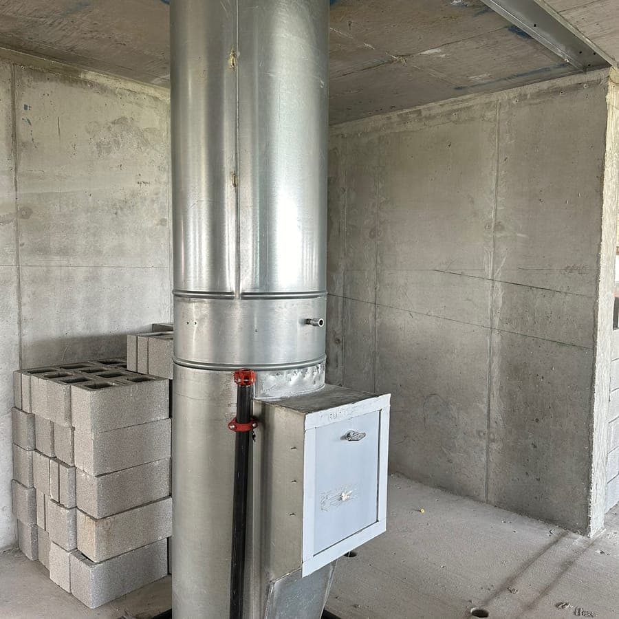 A new steel trash chute standing floor to ceiling in a concrete shaft, with its intake door fitted