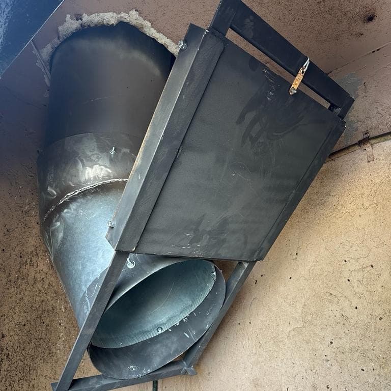 A guillotine fire damper in its steel frame at the bottom of a trash chute