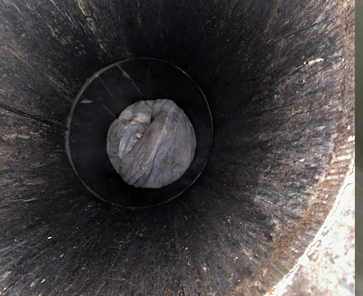 Looking up a trash chute caked shut with waste